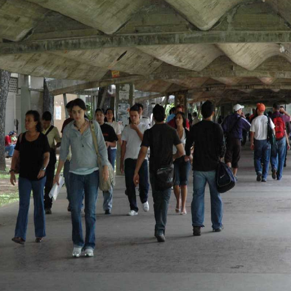 Incrementa la diáspora de profesores y estudiantes en las universidades en Venezuela por la crisis económica. La mayoría de las universidades en Venezuela, por no decir todas, están al borde de un cierre técnico. El presupuesta asignado para el nuevo semestre que inició a mediados de febrero de 2018 apenas alcanzaba para unas dos semanas. Actualmente continúan el semestre sin muchos de los beneficios que antes percibían, como transporte o comedor. La hiperinflación en el país se ha consumido todo. Toda esta situación ha generado una diáspora de profesores, no solo en las universidades en Venezuela, también en colegios públicos y privados. Los estudiantes también desertan, unos para ingresar a tiempo completo al campo laboral, otros porque se van del país sin culminar sus estudios. Universidades en supervivencia La Universidad del Zulia (LUZ) es una de las casas de estudio que reorganizó sus horarios para frenar la deserción estudiantil y laboral. Se trata de una medida con la que solo asisten a clases presenciales en un máximo de tres días a la semana. Esto para minimizar los inconvenientes por falta de transporte, ya que tanto en la mañana como en la tarde se complica tomar un bus y llegar al lugar de destino. A ello se suma la falta de dinero en efectivo para pagar el pasaje, y la delincuencia que acecha a las unidades. En la Universidad Nacional Experimental de Guayana (UNEG) y la Universidad Experimental Politécnica Antonio José de Sucre (Unexpo), en Puerto Ordaz, pasan por la misma situación. También han recortado horarios y se han quedado sin beneficios mínimos, además de los daños de infraestructura. Profesores con salarios de hambre El presidente de la Asociación de profesores dela UNEG, Raúl Brito, señala que un profesor gana quincenalmente 600 mil bolívares, el equivalente al precio de un cartón de huevos. La deserción de profesionales y técnicos en el último trimestre fue de entre 70 y 100 personas. El rector de la Universidad de los Andes (ULA), Mario Bonucci, señaló que el profesor mejor pagado devenga aproximadamente un millón 500 mil bolívares, mientras que la canasta alimentaria en Venezuela se ubicó en más de 24 millones de bolívares en enero de 2018. Con el nuevo incremento salarial que ordenó el presidente Nicolás Maduro se espera que estos precios de la canasta alimentaria se incrementen, así como la hiperinflación y el precio del dólar paralelo. El horario en la UNEG se redujo de 8:00 AM a 1:00 PM para que profesores y personal administrativo puedan hacer un segundo trabajo de ‘rebusque’. Hay profesores que trabajan de taxistas, si cuentan con vehículo disponible, pues la mayoría también debe trasladarse en transporte público, cuya falta de unidades se eleva en más de un 70% según las estimaciones de la Cámara de Transportistas. En los colegios, padres y representantes se organizan para llevar a los docentes, o hacen una recolecta cada cierto tiempo para que puedan cubrir los gastos de transporte. Deserción estudiantil En la Unexpo la deserción estudiantil llega al 40%. El centro de estudiantes de la Escuela de Ingeniería detalla que de tener 4 mil 500 estudiantes el semestre pasado, paso a contar solo con 2 mil 400 inscritos en el ciclo que inició a mediados de febrero. El servicio de comedor en la Unexpo pasó de ofrecer 2 mil 400 comidas a 800 comidas diarias, las rutas de transporte bajaron de 114 a 23 rutas al día. El presupuesto asignado para transporte fue de un millón 400 mil bolívares, y 50 millones para comida para comedor. Los estudiantes se siguen retirando de las universidades en Venezuela por no poder trasladarse a ellas, no tener qué comer ni costear los demás materiales de estudio. Unos han privilegiado el trabajo para ingresos económicos extras en el hogar, todo invertido en comida principalmente.